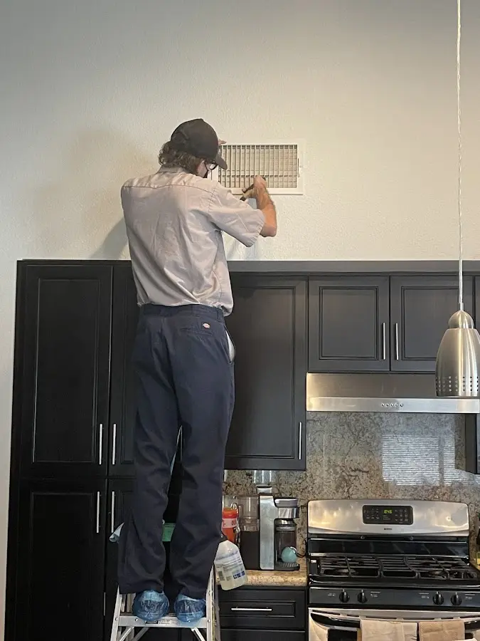 Technician inspecting an air vent during HVAC service in Island Lake